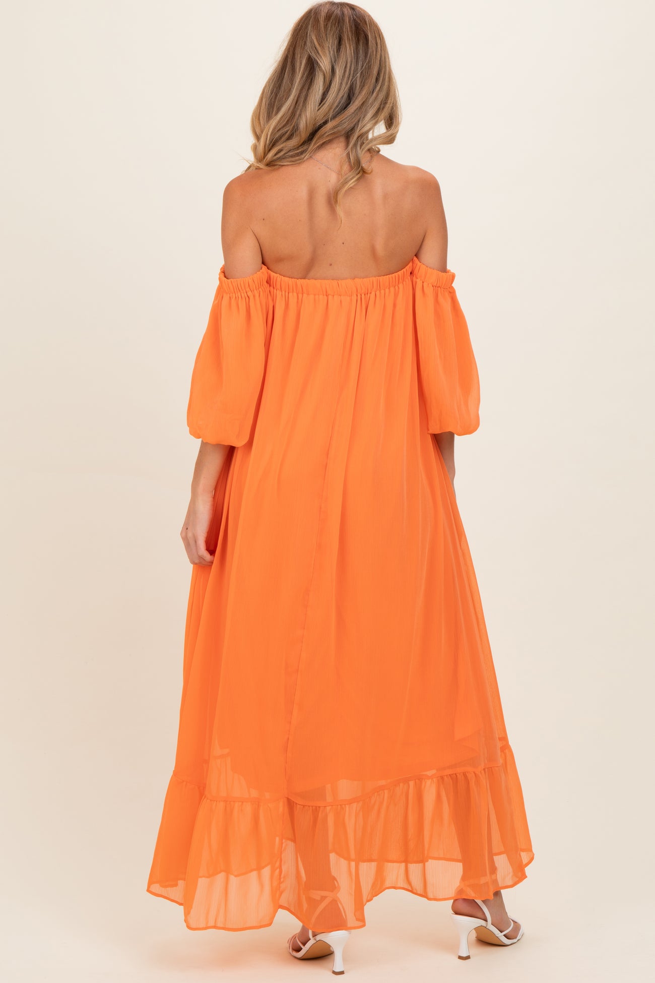 woman wearing an off-the-shoulder orange maternity dress with puff sleeves and a tiered hem