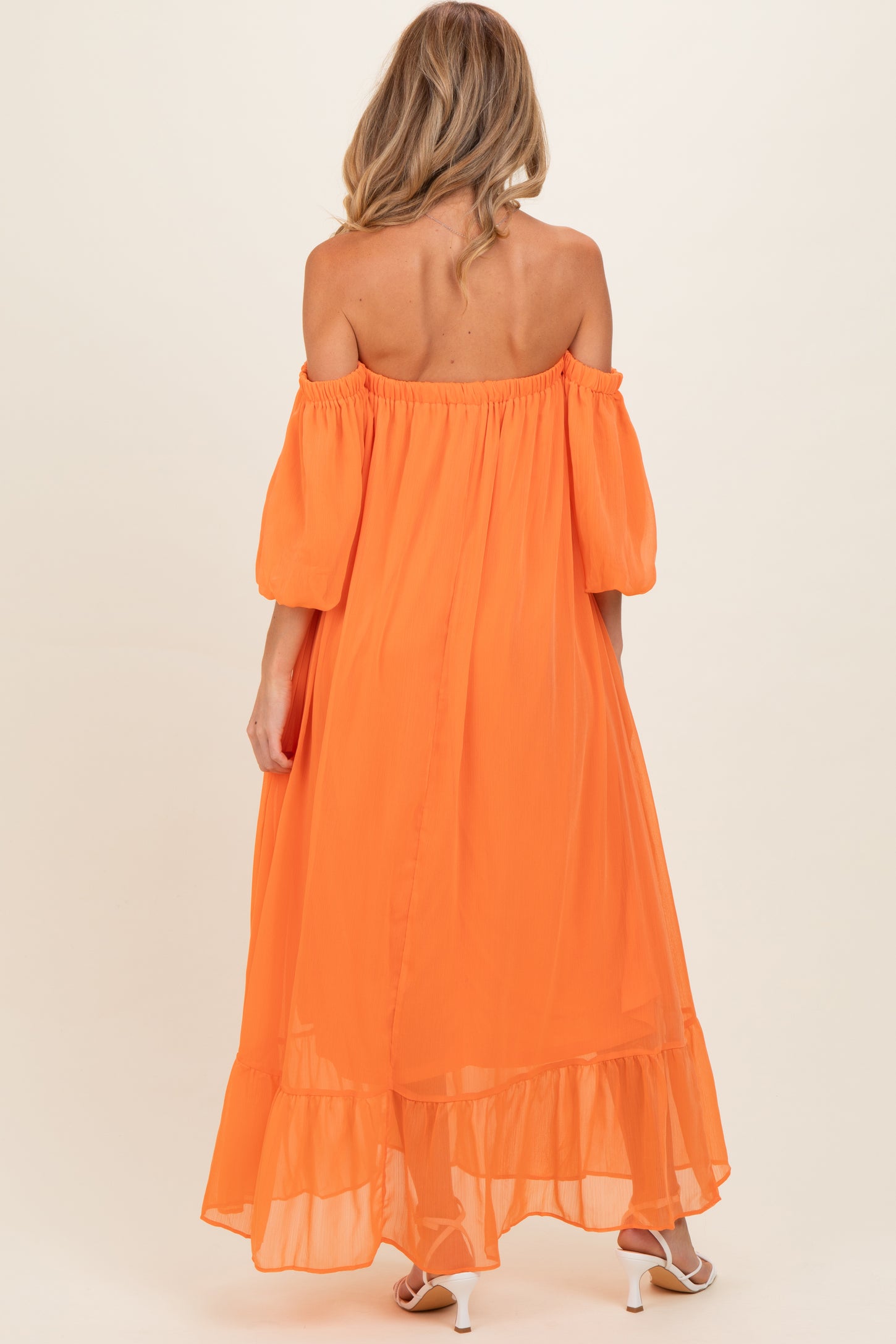 woman wearing an off-the-shoulder orange maternity dress with puff sleeves and a tiered hem