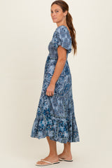 woman wearing a blue floral print maxi dress with short puff sleeves and a tiered skirt
