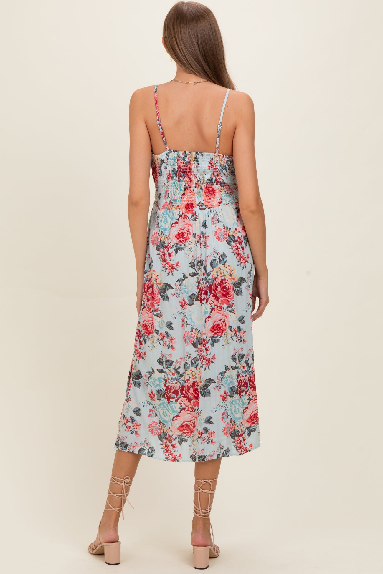 woman wearing a floral print maternity dress with a smocked back and adjustable straps, featuring a mid-length flowy skirt