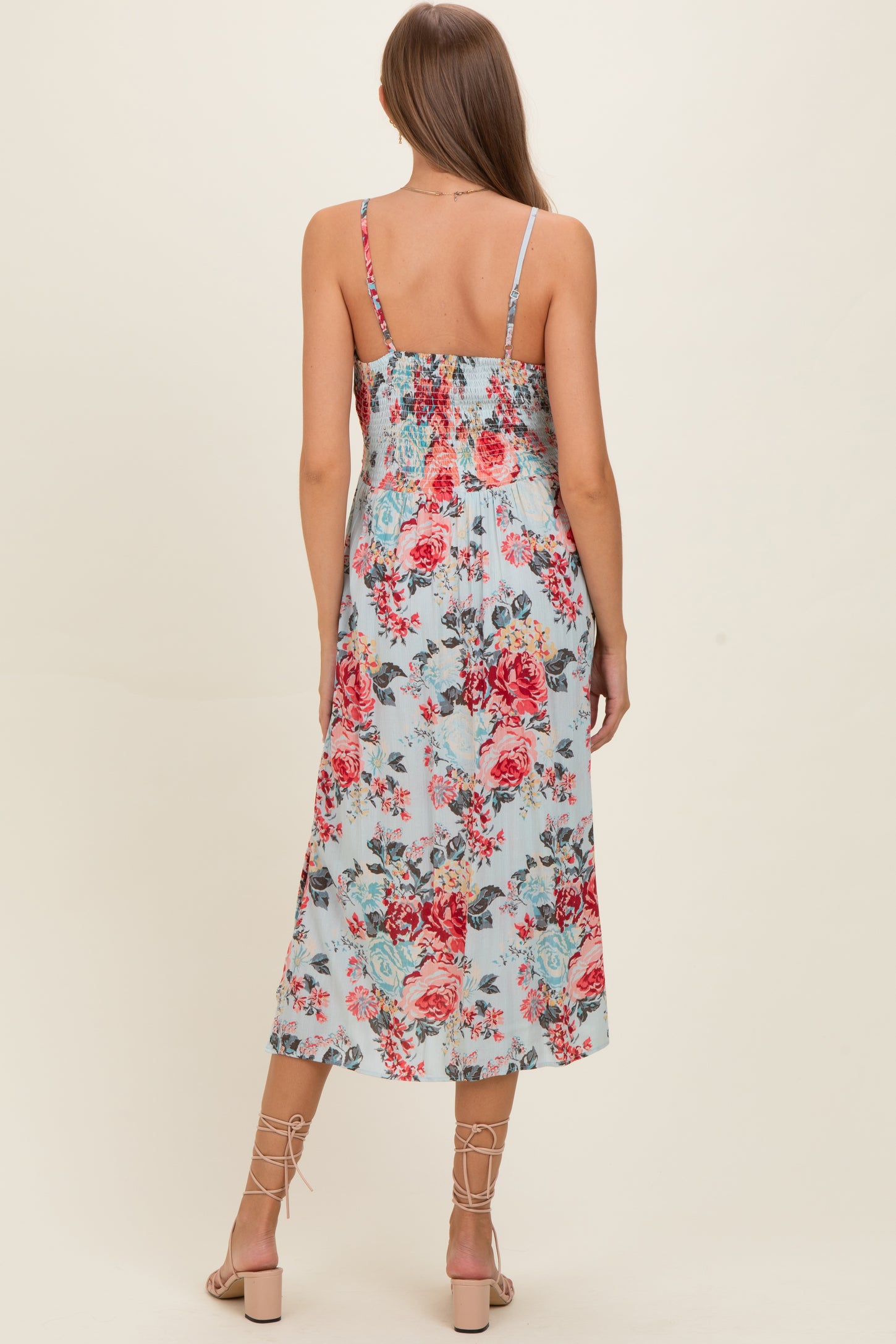 woman wearing a floral print maternity dress with a smocked back and adjustable straps, featuring a mid-length flowy skirt