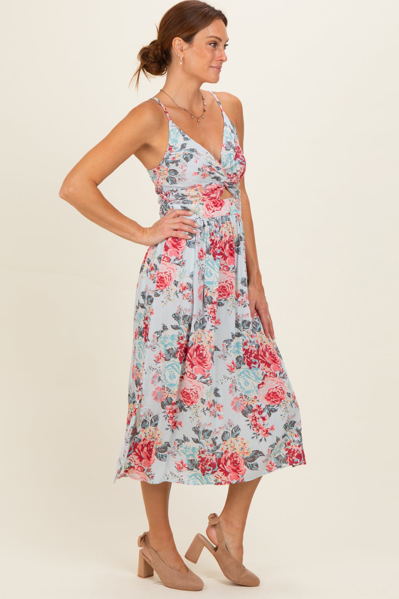 woman wearing a floral print midi dress in light blue with pink and red roses, styled with tan block heel shoes