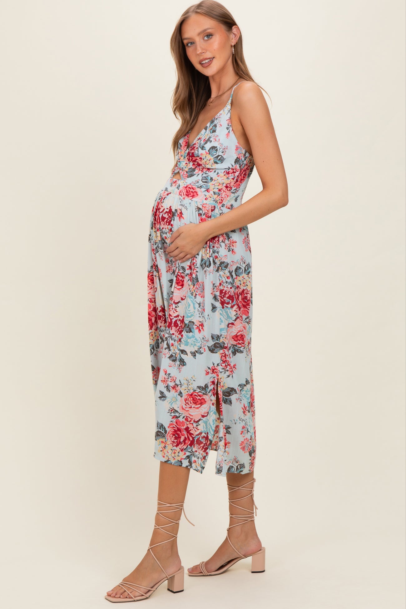 woman wearing a light blue floral maternity dress with a v-neckline and holding her baby bump