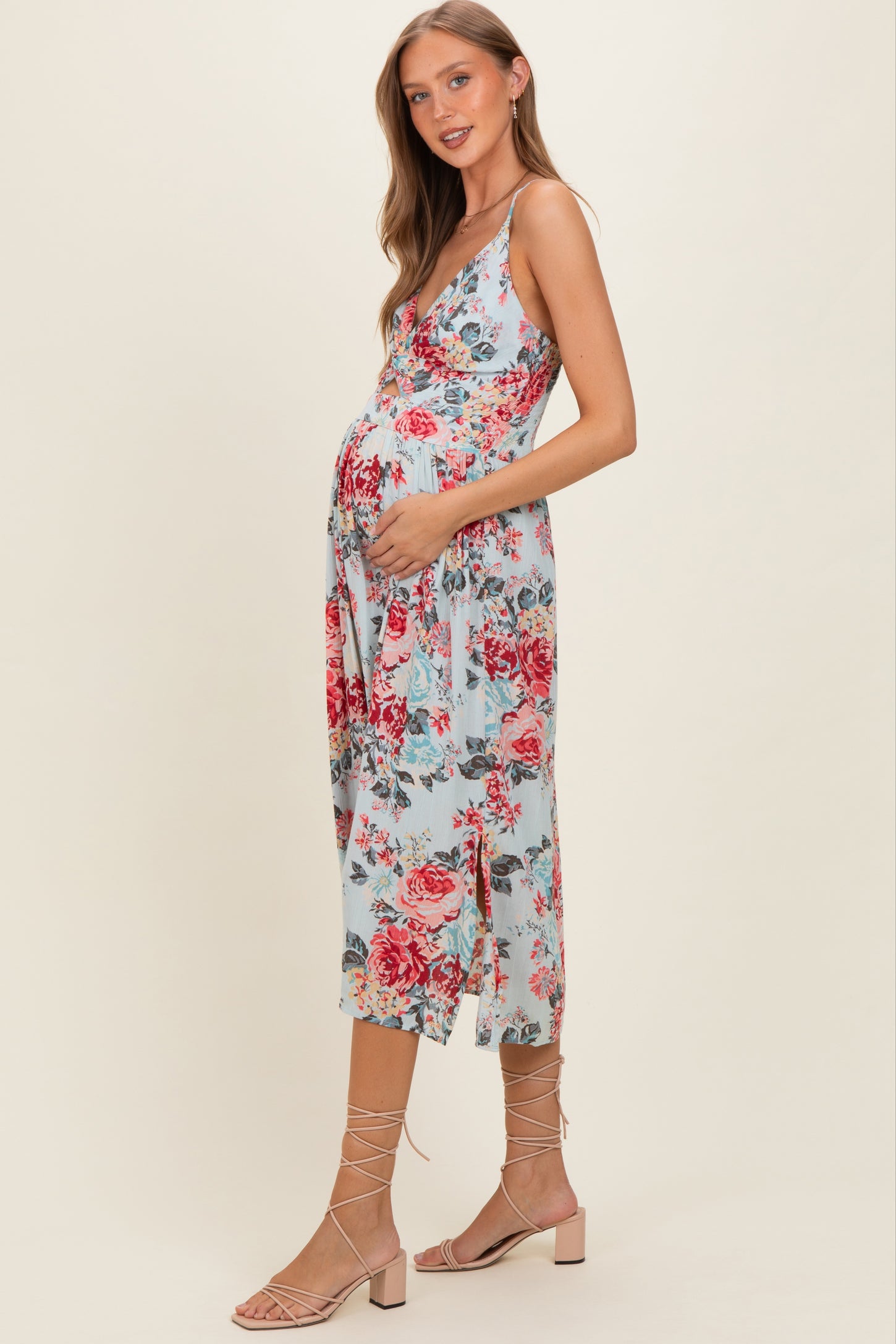 woman wearing a light blue floral maternity dress with a v-neckline and holding her baby bump