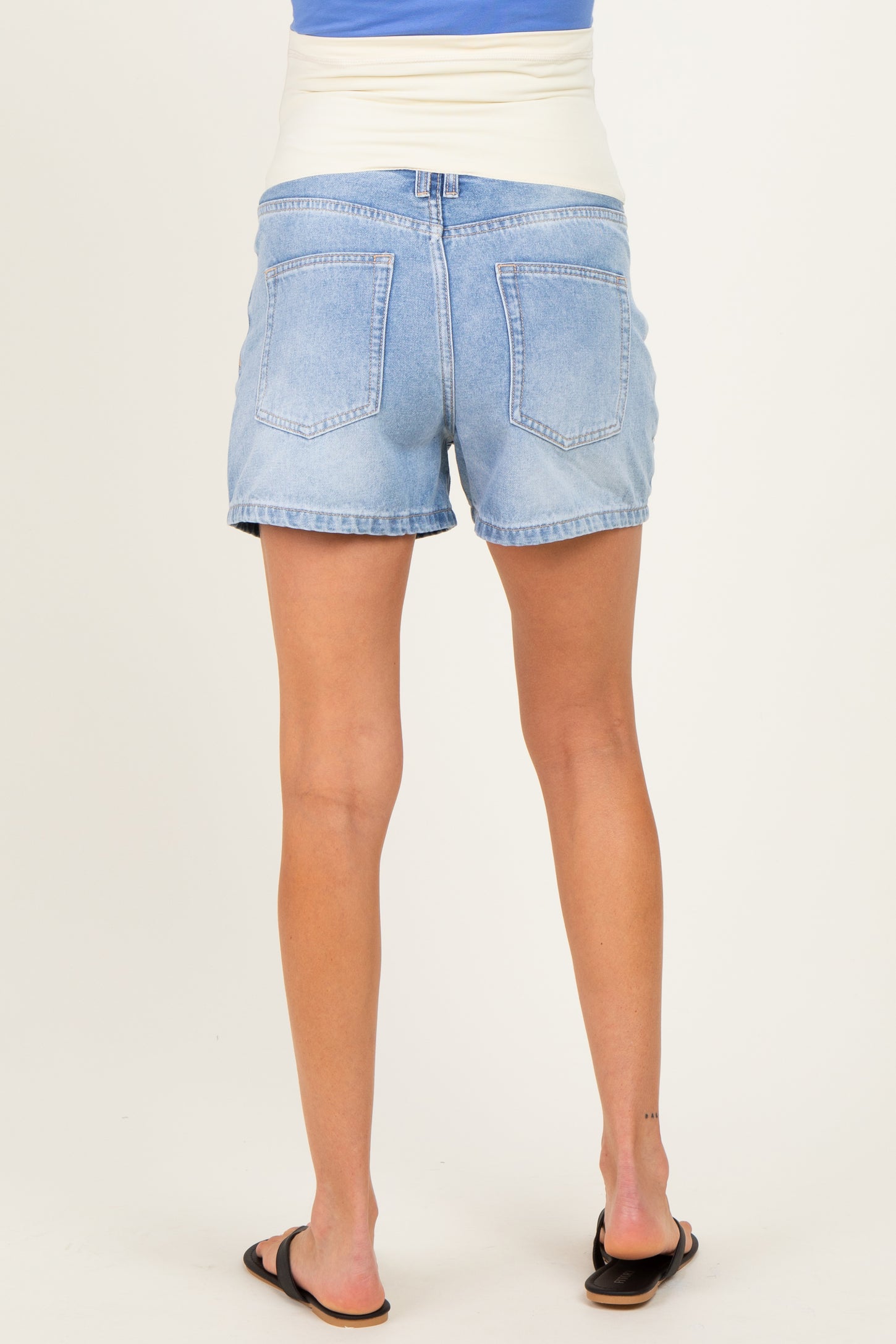 woman wearing light blue maternity denim shorts, showing the back view