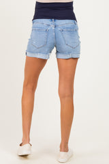 woman wearing maternity light wash denim shorts with a rolled hem and a navy blue waistband