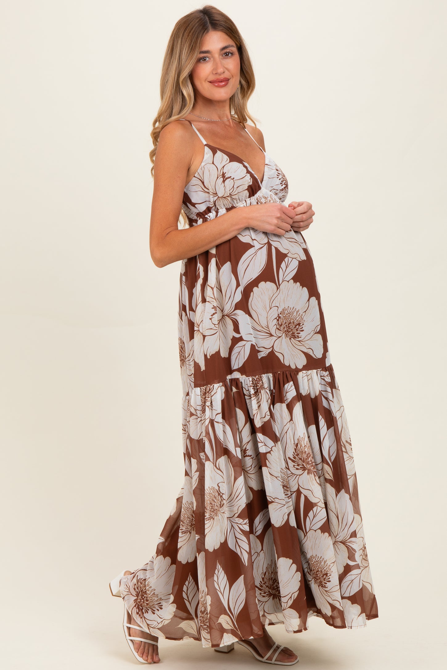 woman wearing a brown floral maternity maxi dress with a tiered skirt and a visible baby bump