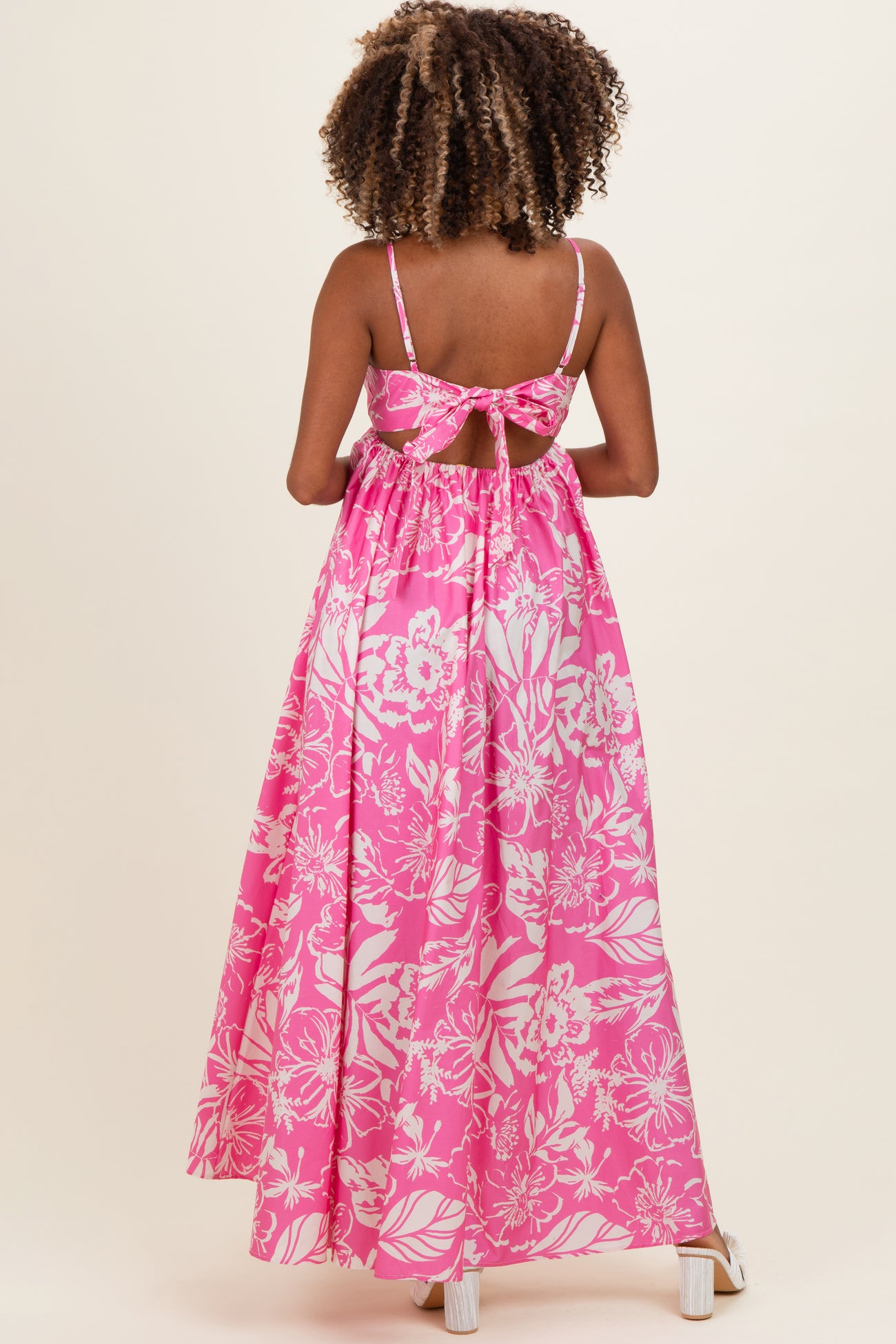 woman wearing a pink floral maternity maxi dress with a bow back detail