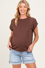 woman wearing a brown short sleeve maternity top and denim shorts, highlighting her baby bump
