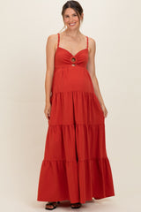woman wearing a red maternity maxi dress with a tiered skirt and cutout detail, showing her baby bump