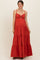 woman wearing a red maternity maxi dress with a tiered skirt and cutout detail, showing her baby bump