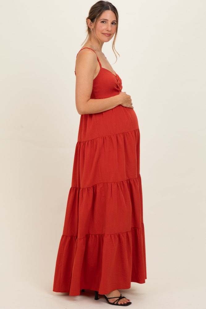 woman wearing a red tiered maxi maternity dress and holding her baby bump