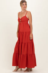 woman wearing an orange tiered maxi dress with a front knot detail and thin straps