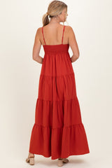 woman wearing a back view of a rust-colored tiered maxi dress with spaghetti straps and a smocked bodice