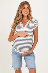 woman wearing a striped maternity top with a v-neck and holding her baby bump, paired with denim shorts