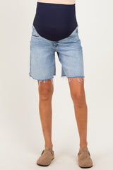 woman wearing blue maternity shorts with a dark waistband and frayed hems, showcasing a baby bump