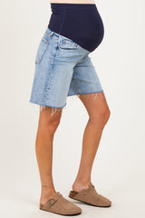woman wearing light wash maternity denim shorts with a high waistband and frayed hem, showcasing her baby bump