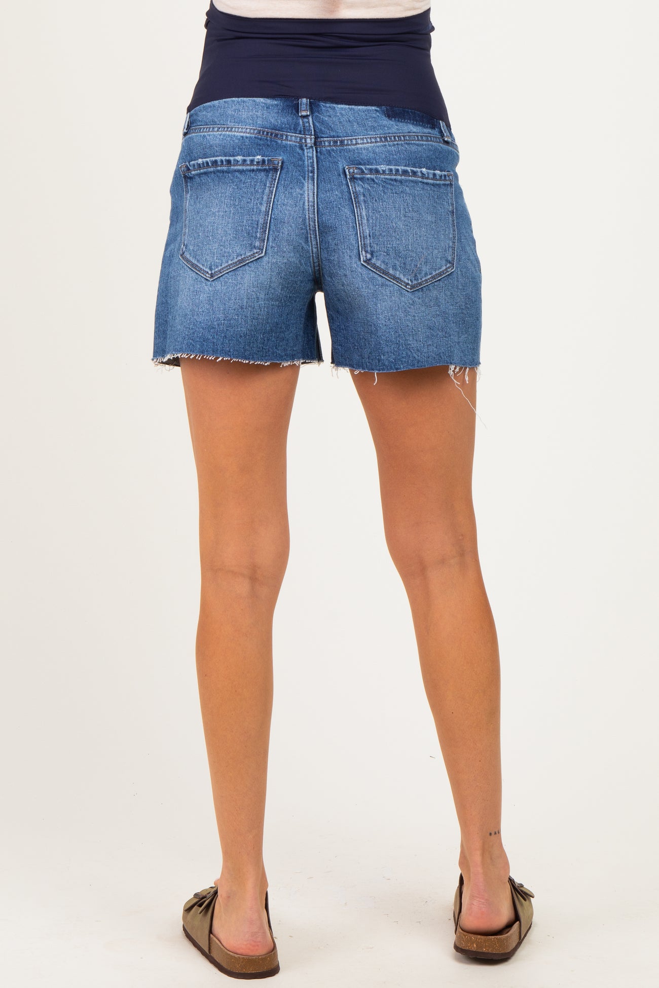 woman wearing a pair of blue maternity denim shorts with a stretchy waistband and frayed edges