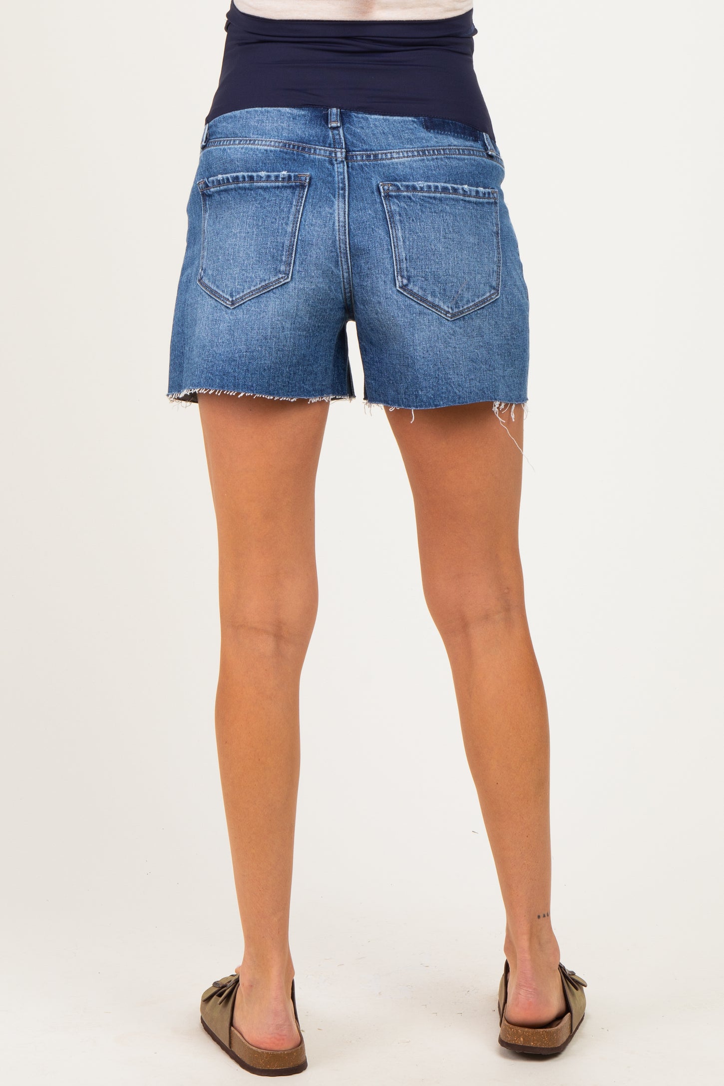 woman wearing a pair of blue maternity denim shorts with a stretchy waistband and frayed edges