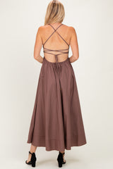 woman wearing a brown maxi dress with a crisscross back and tie details, viewed from the back