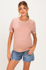 woman wearing a beige and red striped maternity t-shirt with puffy sleeves and blue denim shorts, showing her baby bump