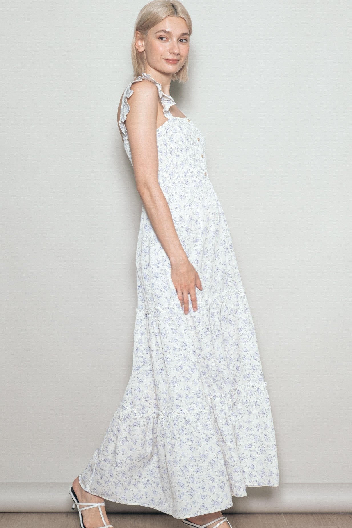 woman wearing a white floral maxi dress with ruffled straps and a tiered skirt