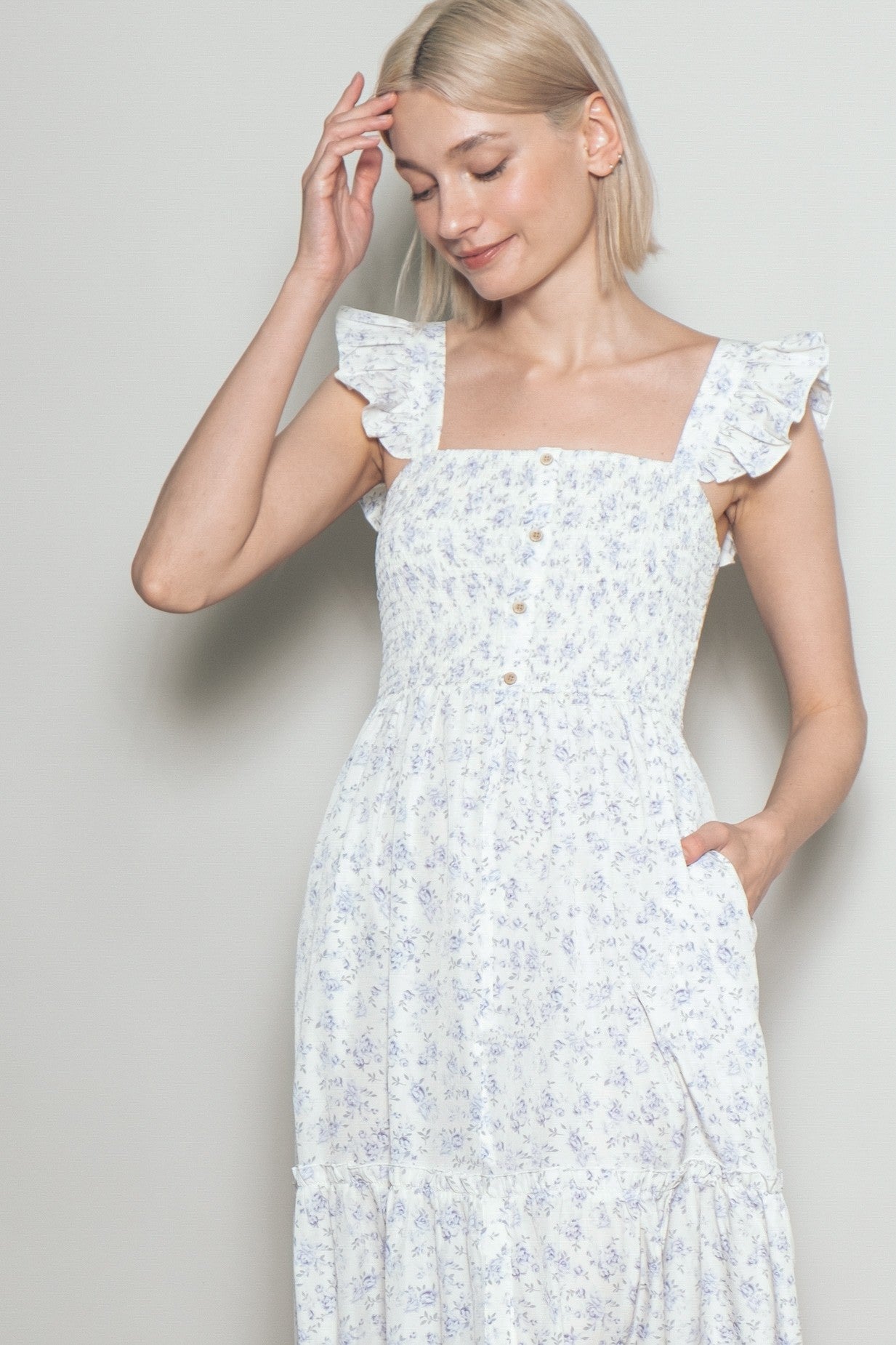 woman wearing a white floral print maxi dress with ruffled shoulder straps and a square neckline