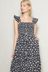 woman wearing a black floral maxi dress with ruffle sleeves and button details