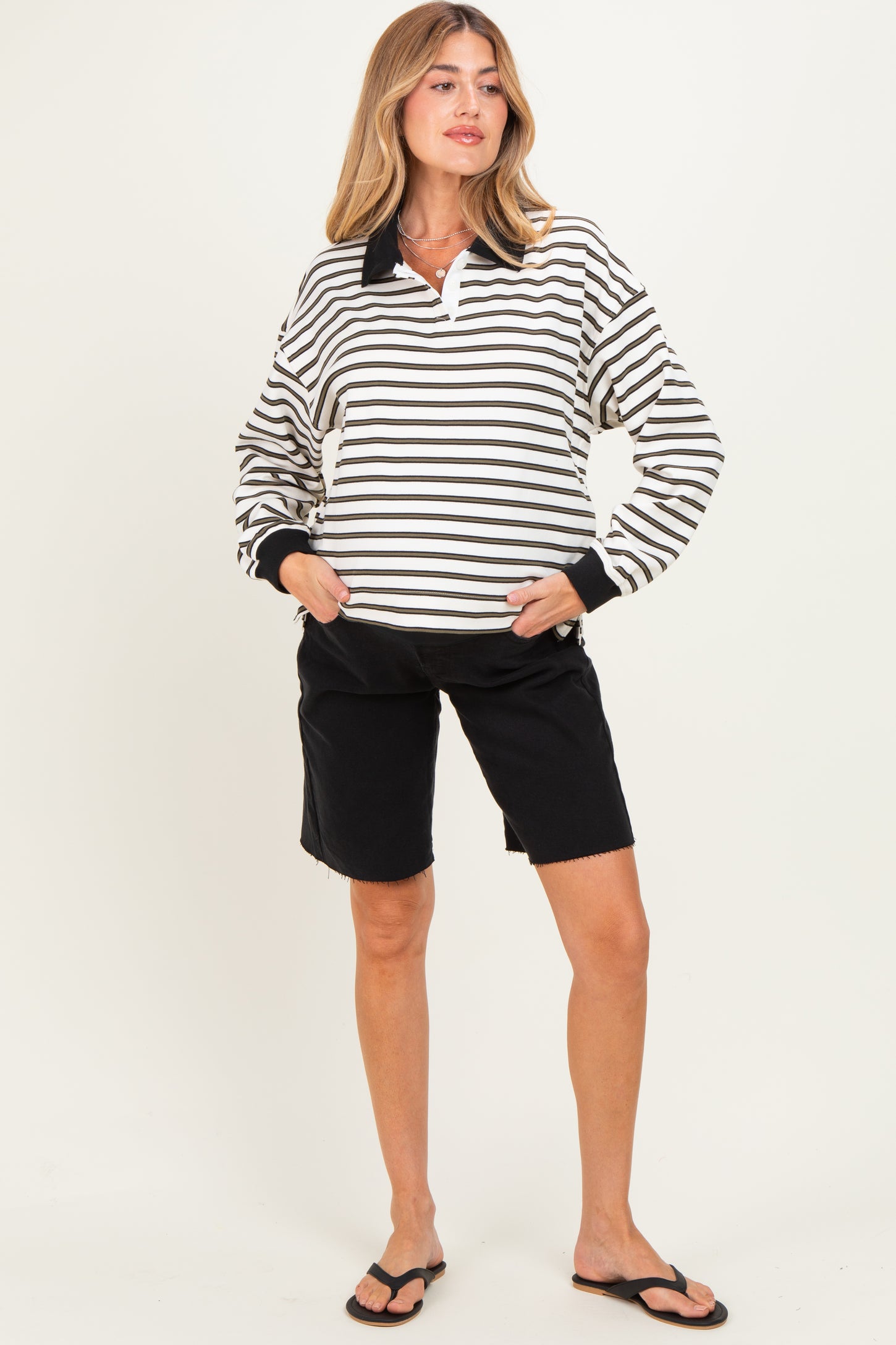 woman wearing a black and white striped maternity pullover with a collar and black maternity shorts