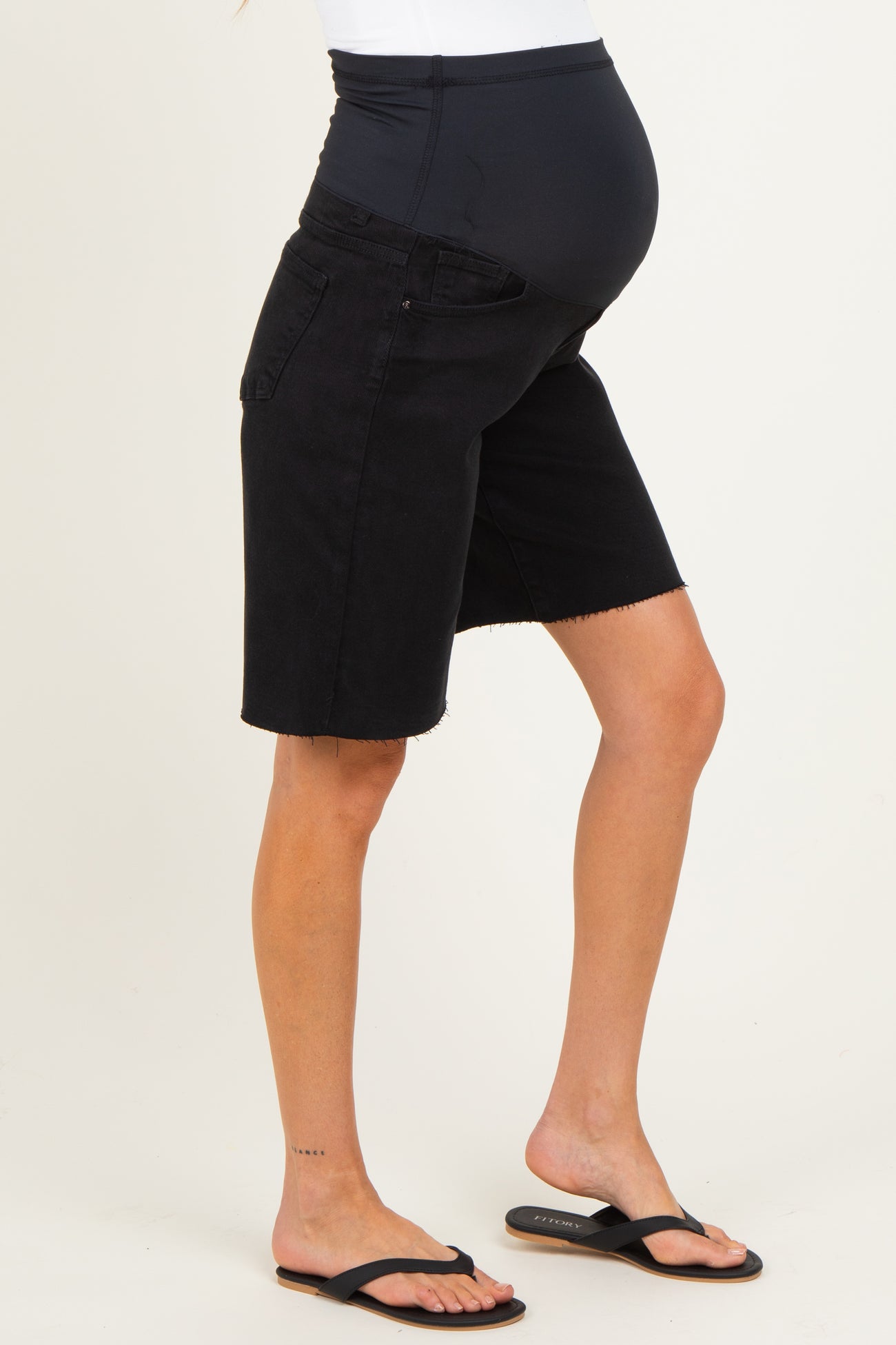 woman wearing black maternity denim bermuda shorts, showcasing a visible baby bump