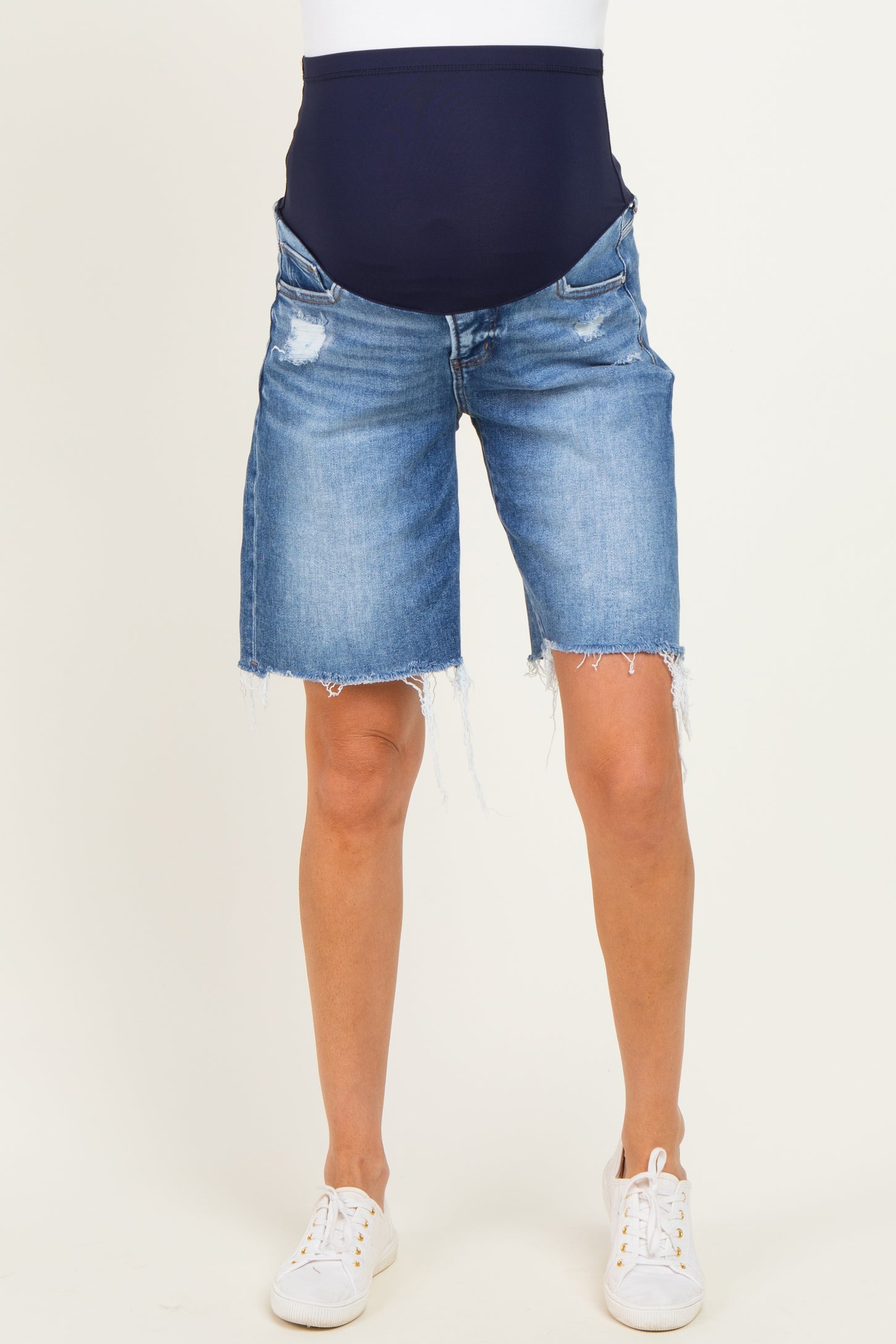woman wearing light blue maternity denim bermuda shorts with a navy blue over-the-bump waistband and distressed details