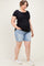 woman wearing a black short sleeve maternity top and blue denim maternity shorts, showing her baby bump