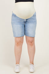 woman wearing light blue denim maternity shorts with a supportive beige belly band, styled with white sneakers