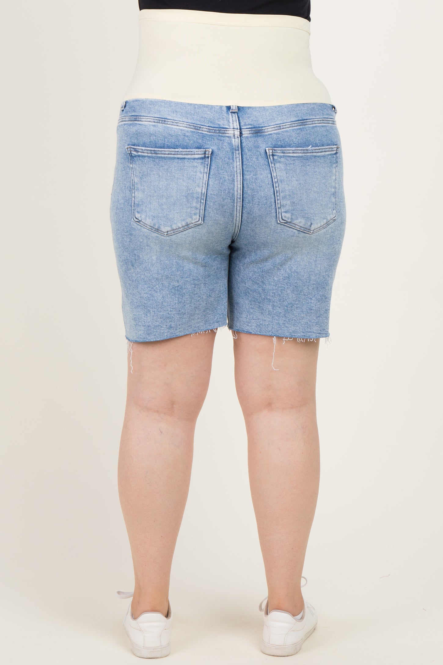 woman wearing maternity plus light blue denim shorts with a supportive waistband, viewed from the back