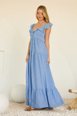 woman wearing a blue striped maxi dress with ruffle sleeves and button detail, standing against a light backdrop