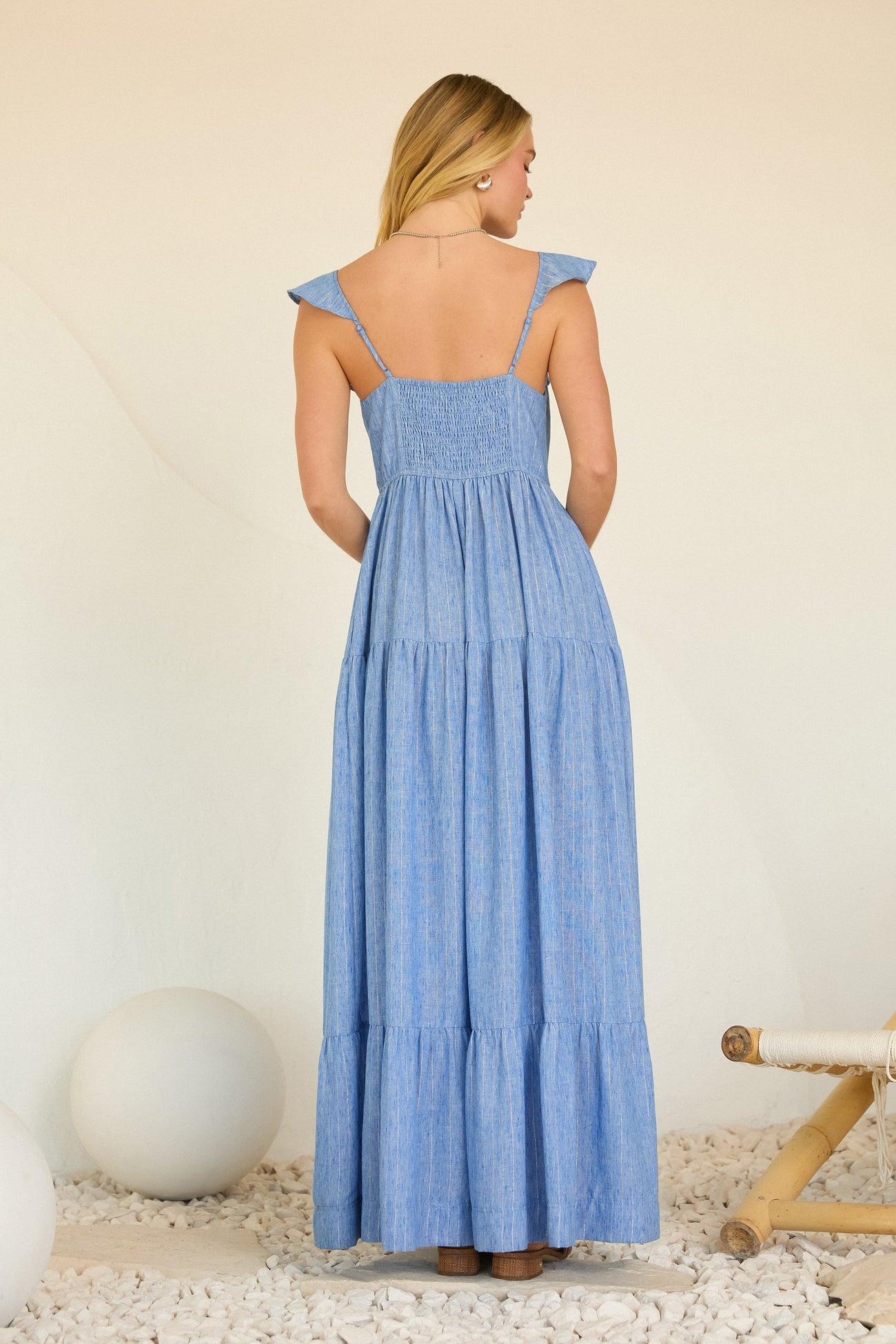 woman wearing a back view of a light blue tiered maxi dress with ruffled shoulder straps