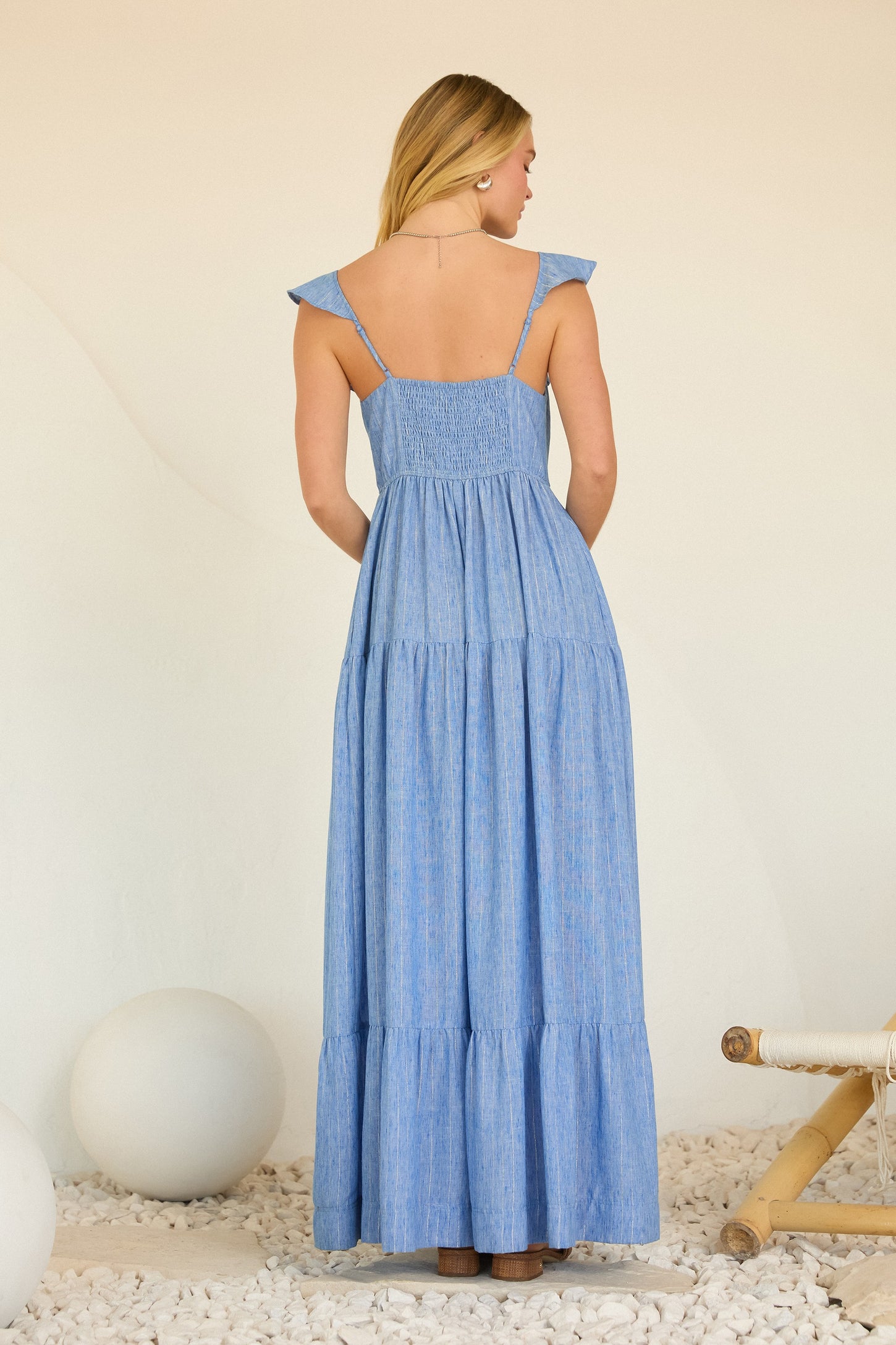 woman wearing a back view of a light blue tiered maxi dress with ruffled shoulder straps