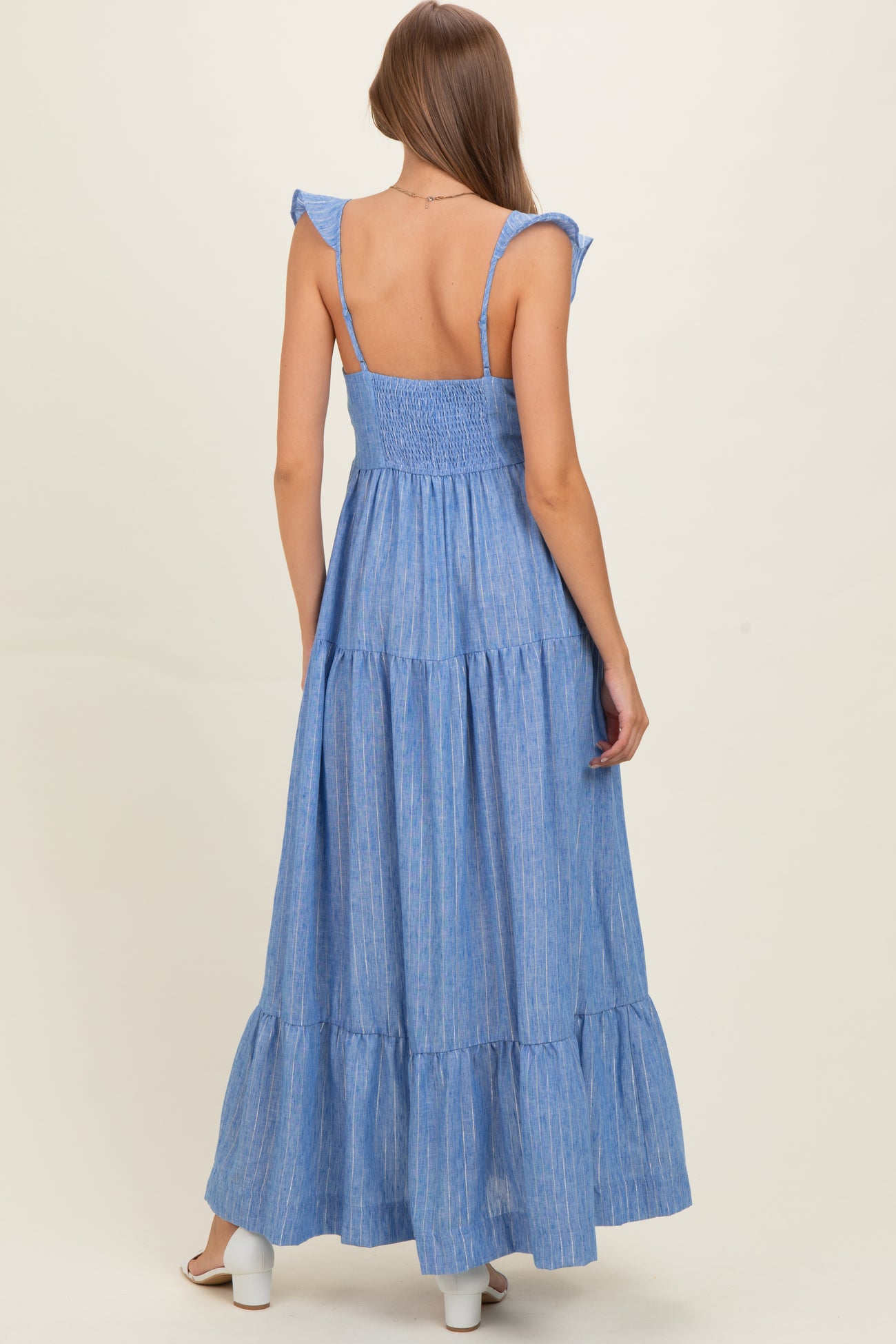 woman wearing a light blue tiered maternity maxi dress with ruffle straps and smocked back