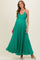woman wearing a green pleated maternity dress with a v-neck and sparkle details, showcasing her baby bump
