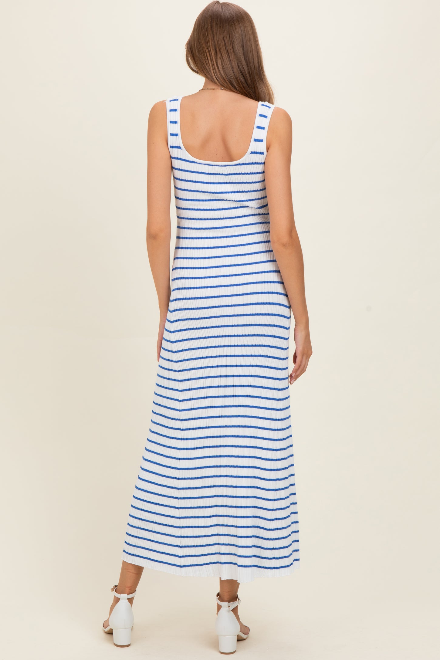 woman wearing a blue and white striped maternity maxi dress with a fitted silhouette and scoop back