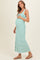 woman wearing a green and white striped maternity maxi dress, gently holding her baby bump