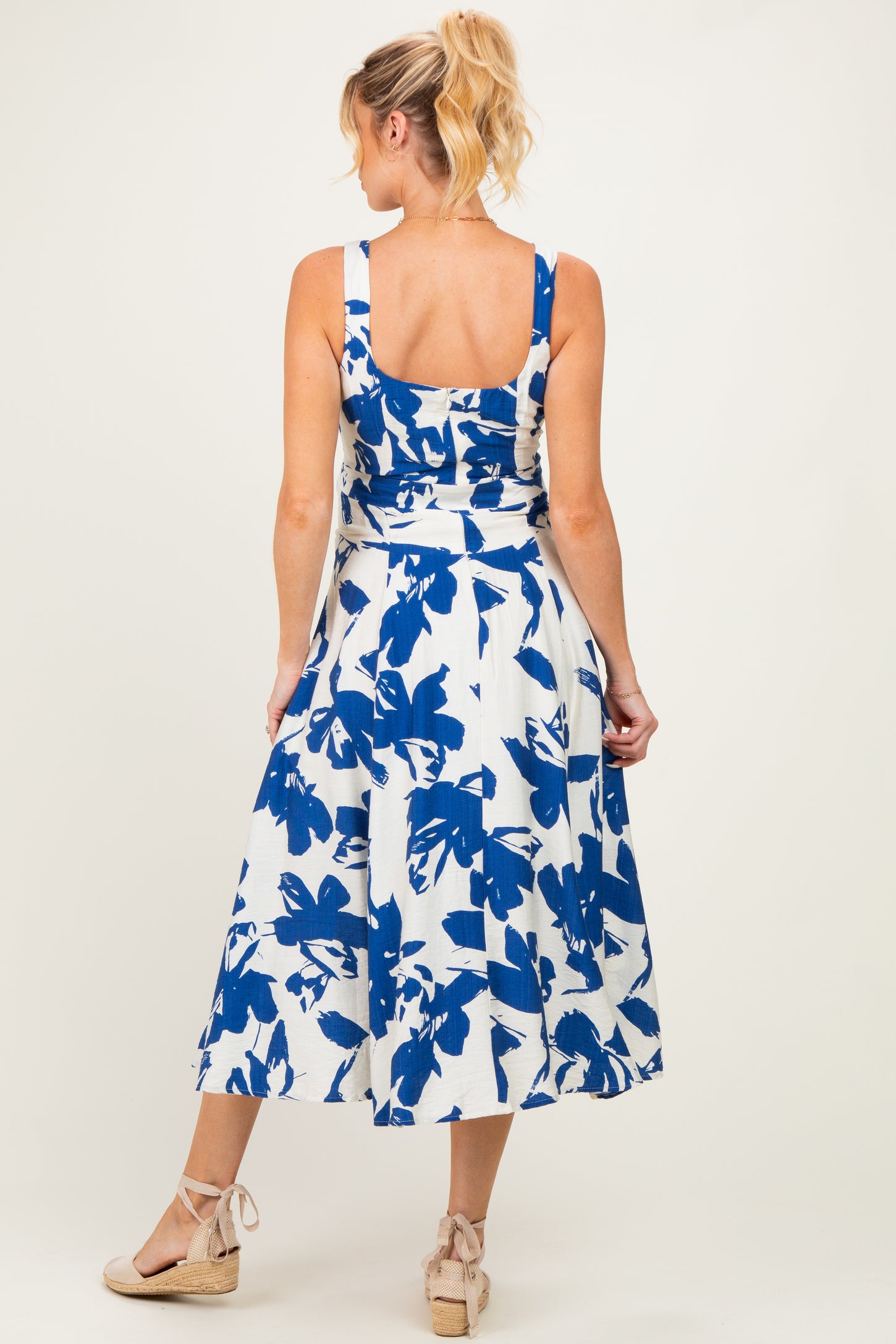 woman wearing a white and blue floral maternity dress with a fitted bodice and flared skirt