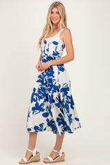 woman wearing a white midi dress with blue floral print, standing in espadrille wedges