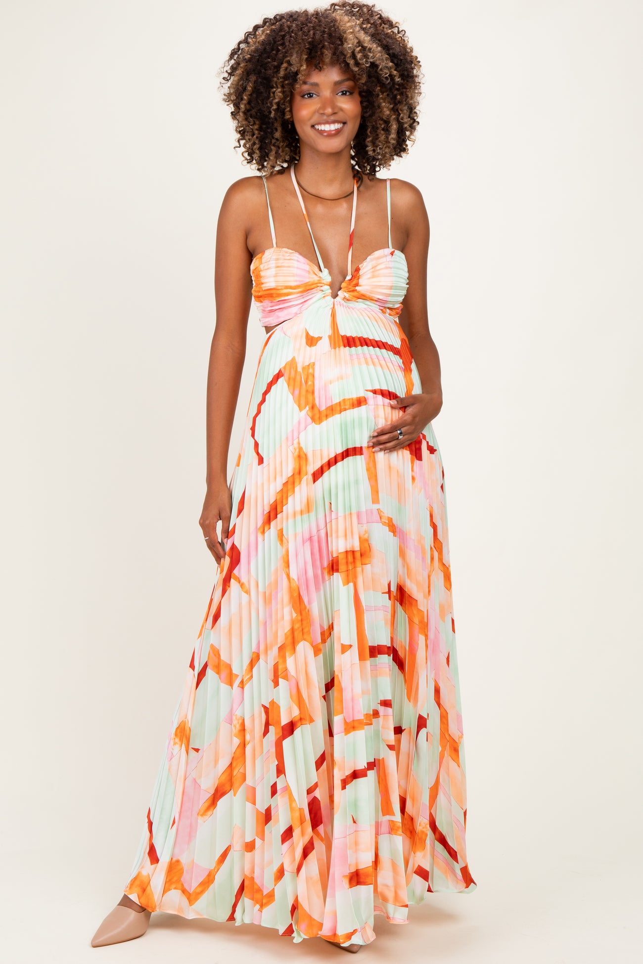 woman wearing a colorful pleated maternity maxi dress with a fitted bodice and adjustable straps, showcasing her baby bump