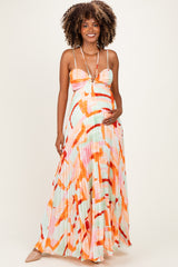 woman wearing a colorful pleated maternity maxi dress with a fitted bodice and adjustable straps, showcasing her baby bump