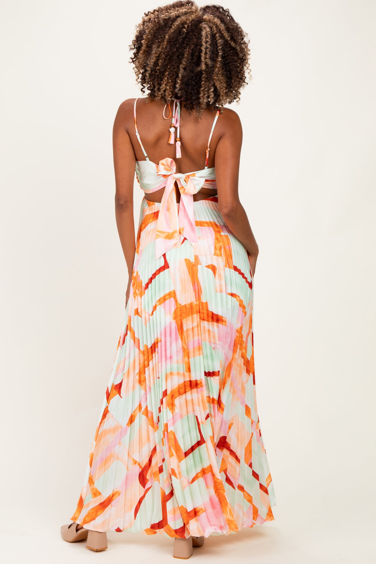 woman wearing a colorful pleated maxi maternity dress with a tie-back detail, showing her baby bump