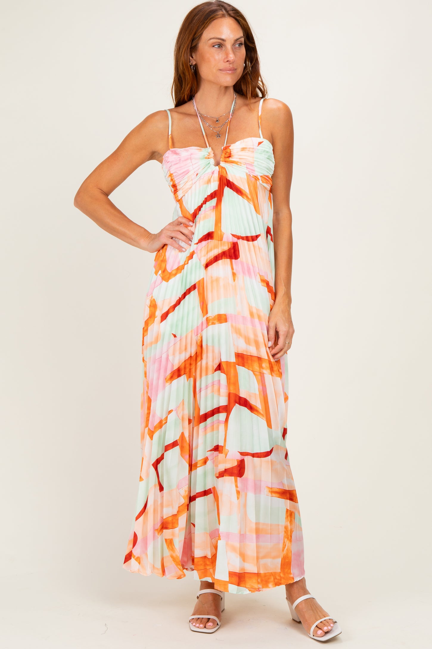 woman wearing a colorful pleated maxi dress with spaghetti straps and an abstract print