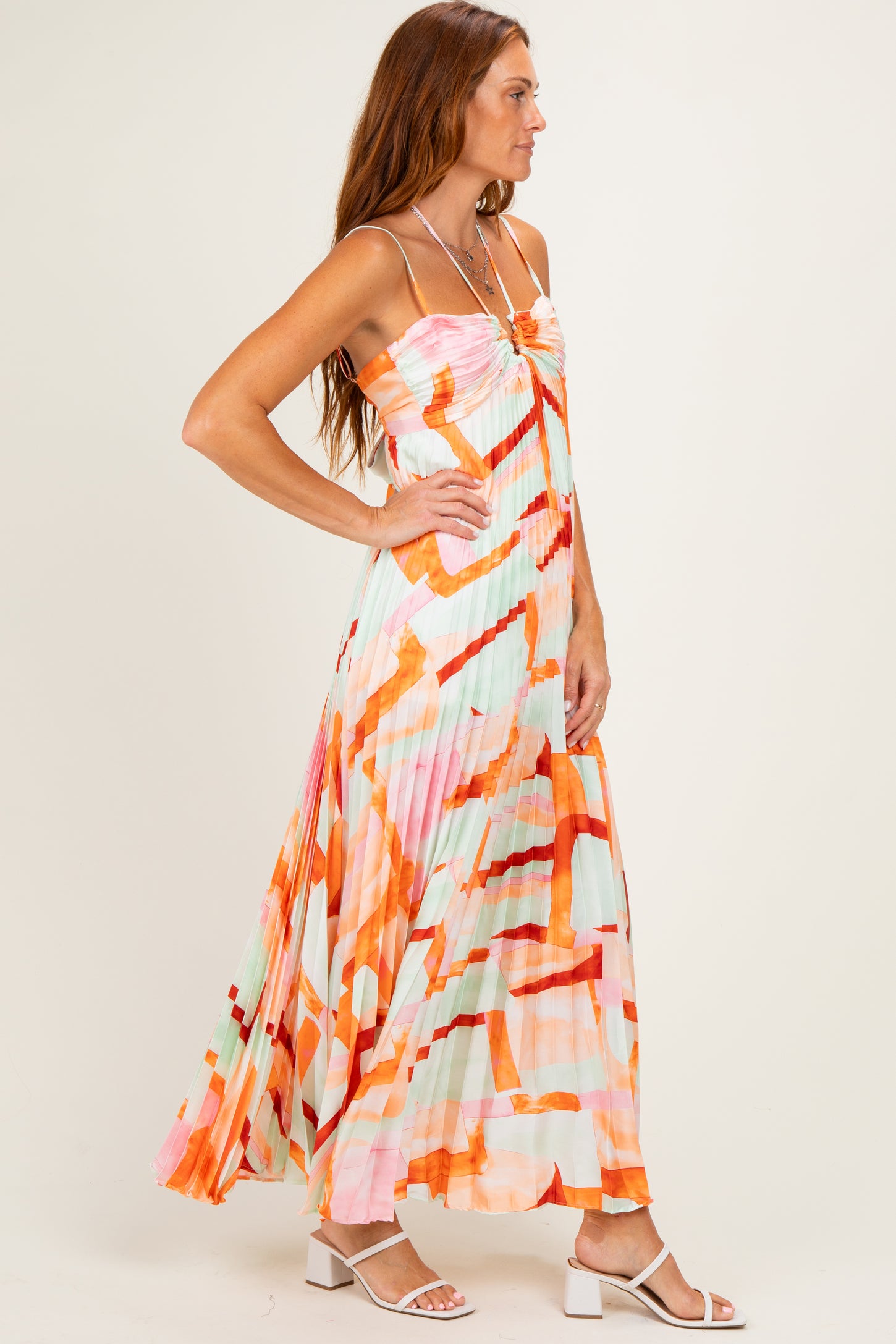 woman wearing a colorful pleated maxi dress with a strapless design and abstract print
