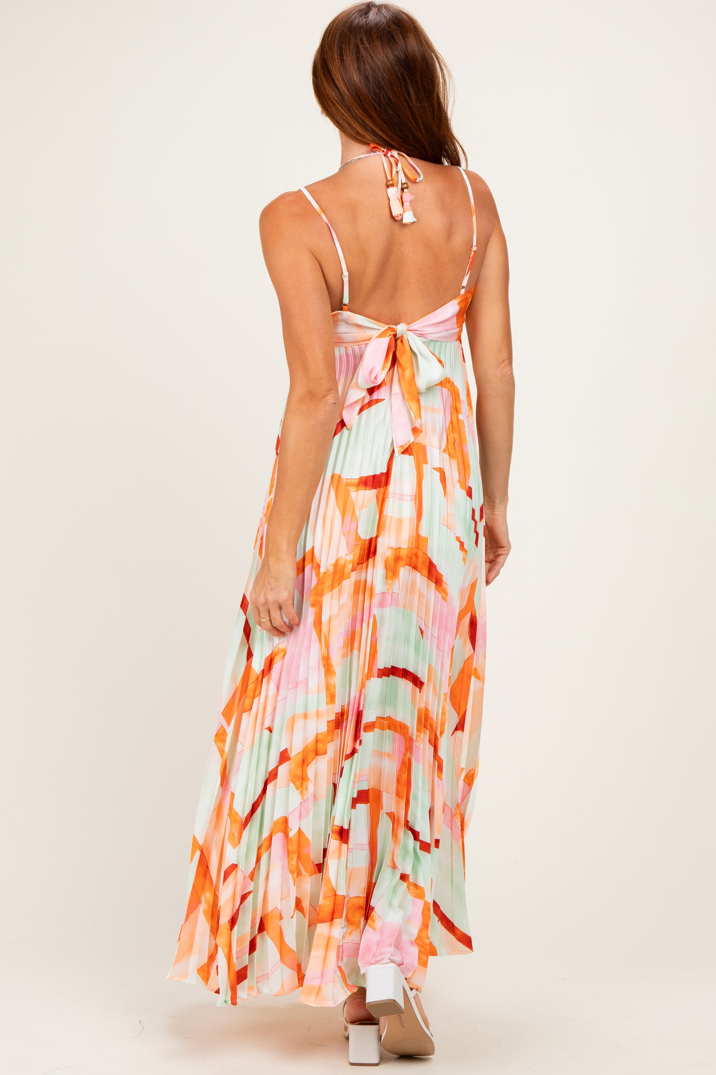 woman wearing a pastel colored maxi dress with a pleated design and tie-back detail
