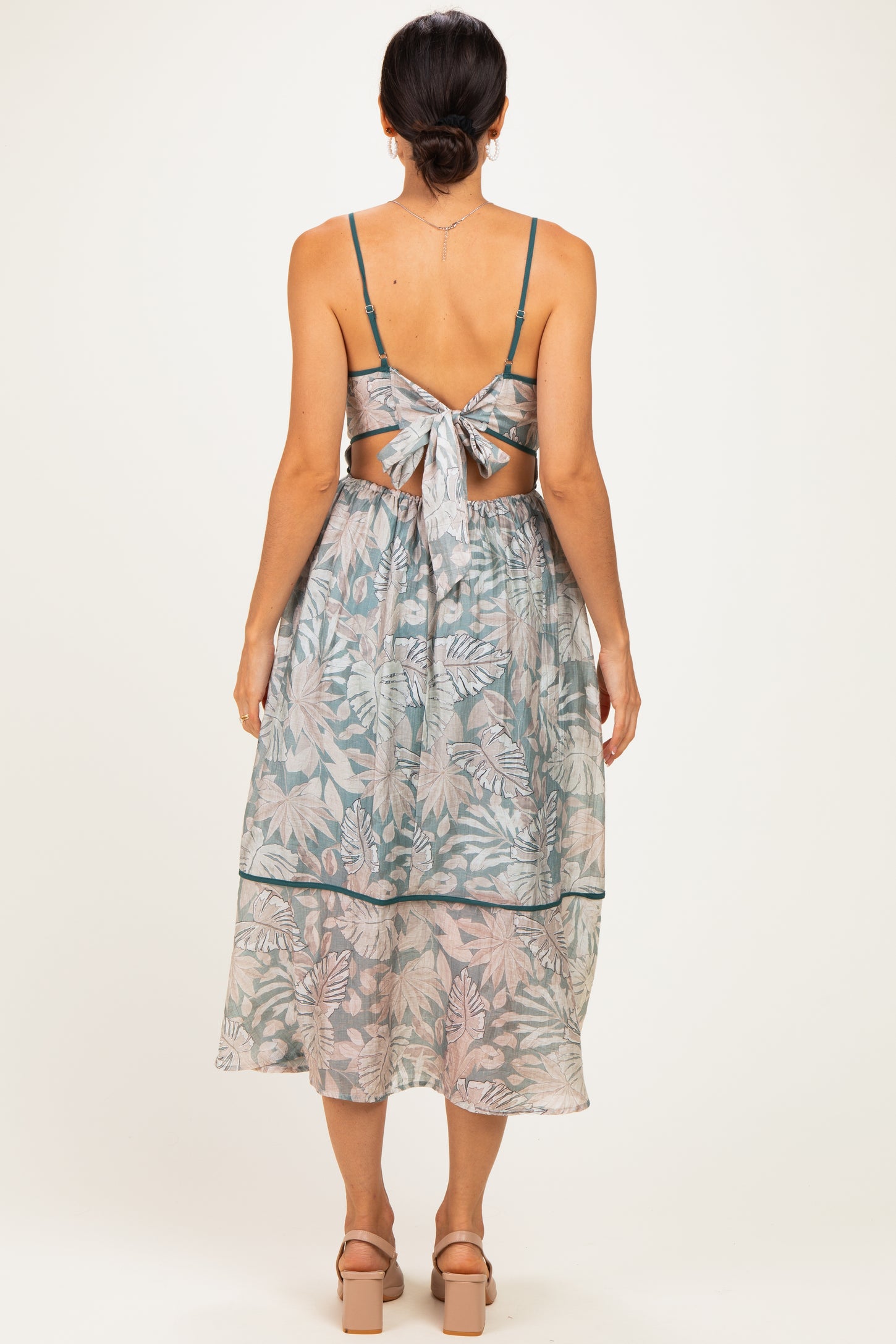 woman wearing a backless floral midi dress with tie detail and a tiered skirt, showcasing a light blue and pink color scheme